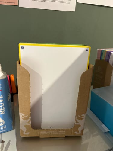 Un client montre un paquet de fiches de révision blanches REVISION 2.0 OXFORD dans son présentoir en carton sur un bureau.
