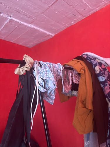 Vista parcial del clóset armable Inkanto de un cliente con ropa colgada en la barra superior.