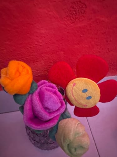 Cliente mostrando su florero de cristal morado con varias flores de felpa adentro.