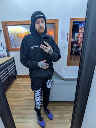 Customer taking a mirror selfie while wearing the black Horror Joggers, showing the 'HORROR' text and graphic on the leg.