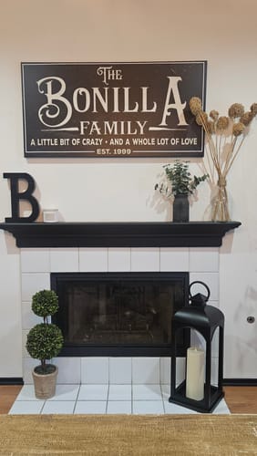 Customer's personalized black Family Sign XXV hanging on a wall above a fireplace.