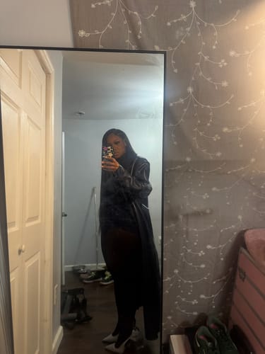 Reviewer's full-length mirror selfie wearing the black Butter Turtleneck Contour Bodysuit styled with a long coat.