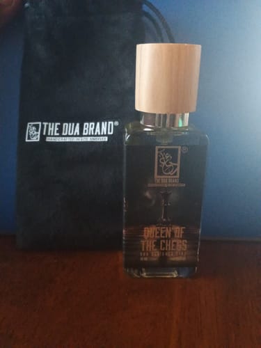Customer's bottle of Queen Of The Chess perfume with a wooden cap, displayed next to a black branded pouch.