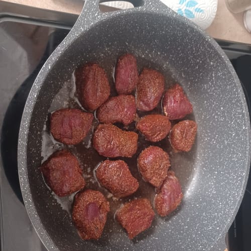 Customer's deer tenderloin steaks, heavily coated in red Brazilian Rub, cooking in a grey pan.