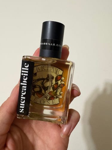Customer holding a square, clear perfume bottle with a black cap.