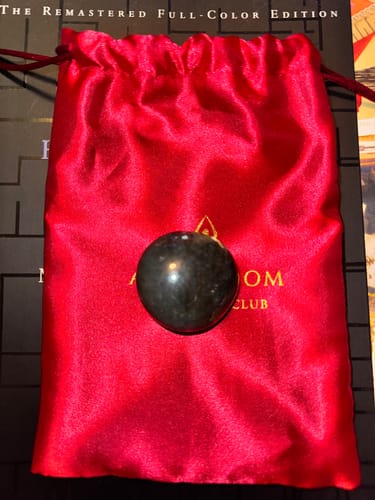 Customer's dark spherical monthly crystal shown on its red satin storage pouch.