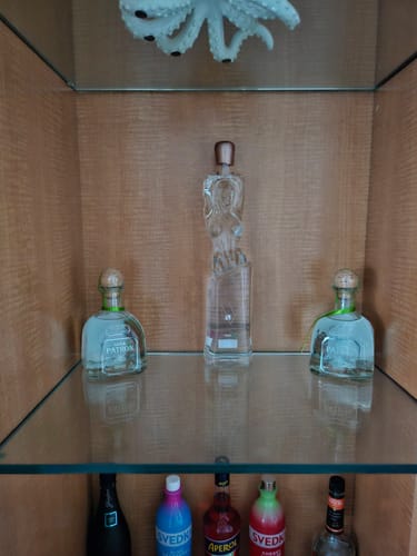 Verified customer photo of a Vavoom Vodka bottle centered on a glass shelf in a wooden home-bar cabinet.