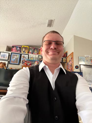 Reviewer wearing the white KUNUFLEX dress shirt layered under a black vest.