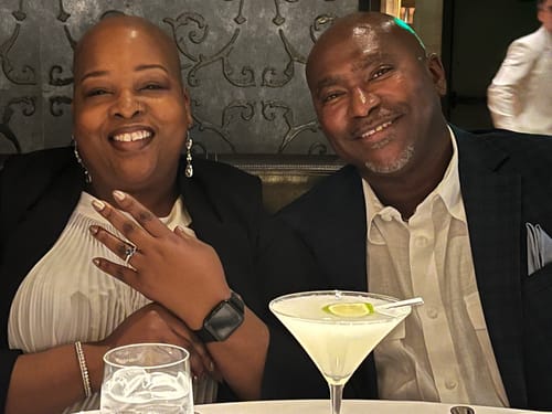 A reviewer and their companion smiling at a table, happy with their personalized song from CREATE YOUR MELODY.