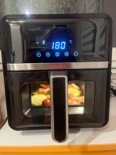Clientul folosește friteuza Novio StonePro neagră, setată la 180°C, cu alimente gătindu-se în interior.