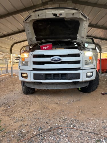Customer's white truck mid-installation, comparing a bright Carifex LED headlight to a dim yellow halogen one.