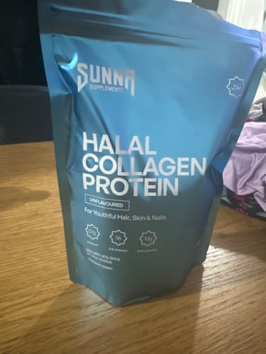 Customer's shiny blue pouch of Halal Collagen Protein standing on a wooden surface.