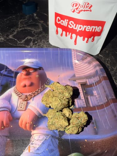 Customer's chunky, green CALI SUPREME THCA Flower buds on a tray with the product's packaging in view.