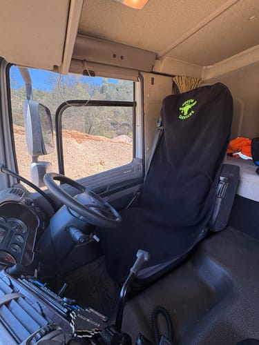 Customer's black Waterproof Car Towel Seat Cover with a custom green logo shown on a truck driver's seat.