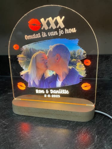 Recensent toont de verlichte 'Omdat ik van je hou' fotolamp met een gepersonaliseerde foto van een kussend stel.