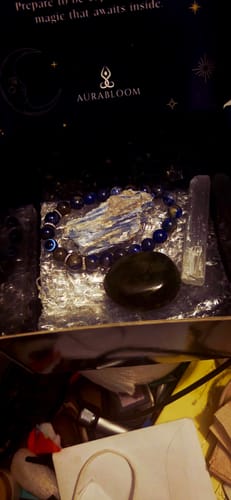 Customer's crystal meditation set showing a blue beaded bracelet, a raw blue and white crystal, and a polished dark stone in a box.