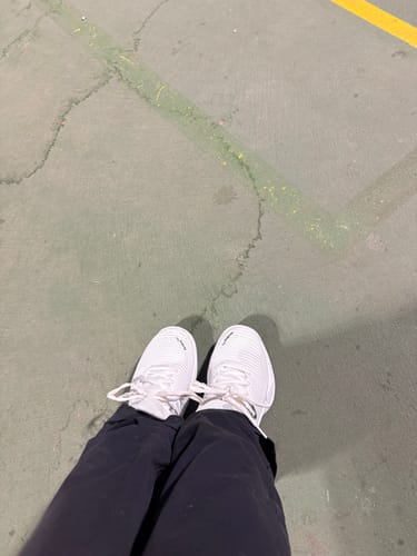 Reviewer's top-down view of their white Hypercourt Express 2 tennis shoes on a court.