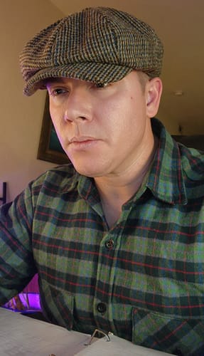 A close-up of a reviewer wearing the brown, eight-panel JP Cap Tweed.