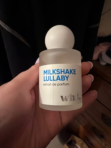 Reviewer holding the frosted glass bottle of Milkshake Lullaby perfume in their hand.
