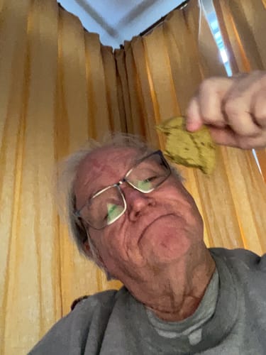 Reviewer holds up a piece of a Cael's Chocolate Chip Cookie in a low-angle photo.