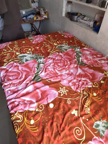 Customer's Flo Float™ Mattress on a bed, covered with a patterned brown and pink bedspread in a room.