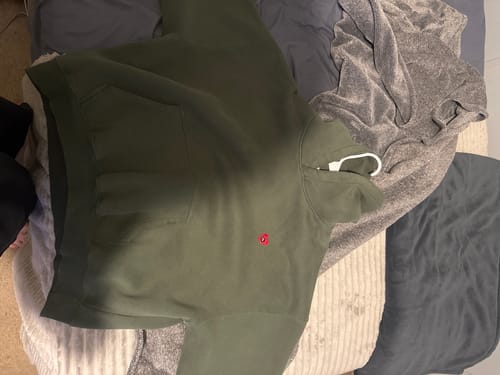 Customer's green Aelfric Eden boxy fit hoodie laid out on a bed.
