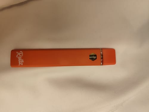 Reviewer's orange ROLLZ THCA Vape pen lying on a white surface.