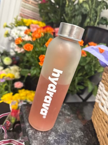 Reviewer's free hydrava glass bottle filled with pink strawberry lemonade electrolyte drink.