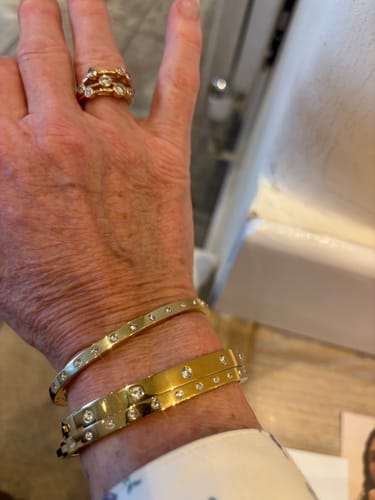 Customer showing a slim Eternity Bangle stacked with other gold bangles on their wrist.
