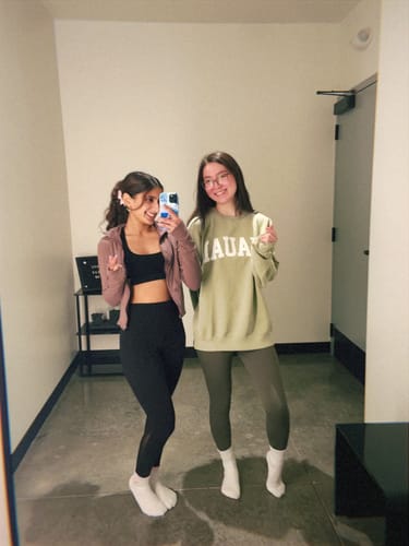 Reviewer with her curly hair held up by a white clip, taking a mirror selfie with a friend.