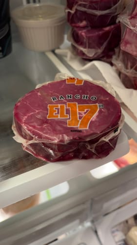 Cliente mostrando un filete cabrería sin hueso fresco y empacado en un estante de refrigerador.