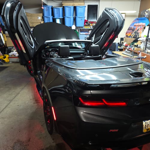 Customer's gray convertible with scissor doors, showing the red glow of the installed LitLamp™ LED Door Sills Pro.
