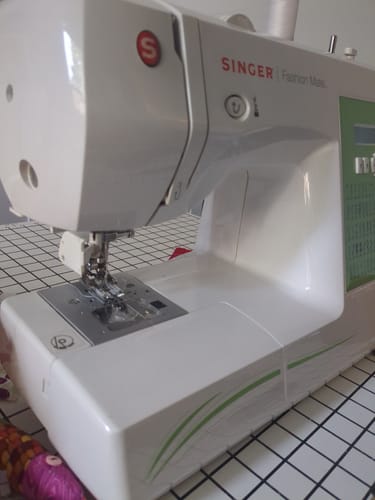 Close-up of the reviewer's Walking Foot attached to a white Singer sewing machine.