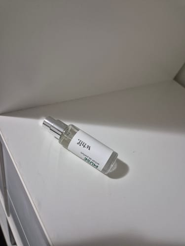 Reviewer's clear bottle of Sultry Muse perfume with a white label, resting on a white surface.