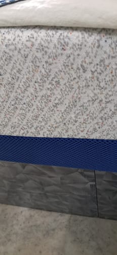 Reviewer's close-up of the Flo Anti-Gravity™ Mattress, highlighting the speckled cover and blue mesh side panel.