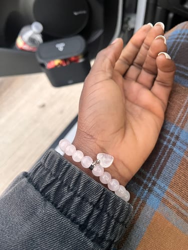 Close-up of a customer's wrist wearing a light pink beaded crystal bracelet with a heart charm.