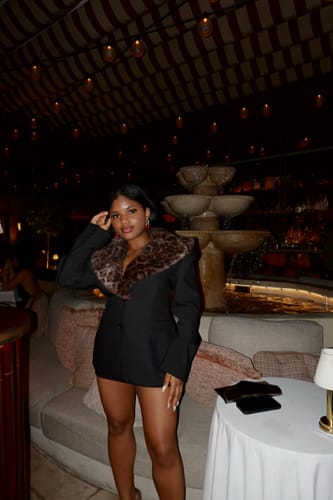Customer wearing the Suiting Faux Fur Leopard Blazer as a dress in a dimly lit restaurant.