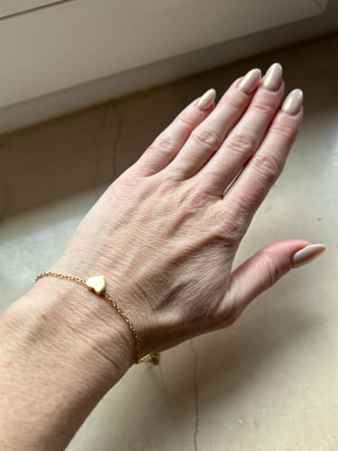 Customer wearing the delicate, gold Little Heart bracelet on their wrist.