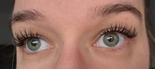 Rezensentin zeigt das Ergebnis des LASH BABY STARTER KITs mit vollen, geschwungenen Wimpern.