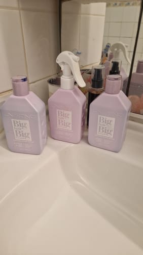 Le client montre le kit complet Peptides Blond Repair, composé de trois flacons, sur un lavabo de salle de bain.
