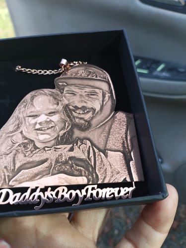 Customer holding a custom photo engraved pendant with a detailed image of a man and child and text 'Daddy's Boy Forever'.