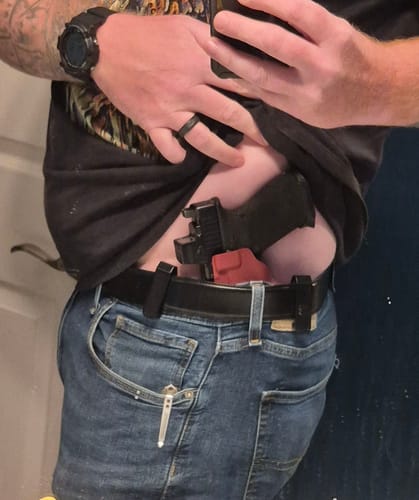 Reviewer showing the T1-ECHO holster worn in the strong-side carry position, tucked inside their jeans and secured with a belt.