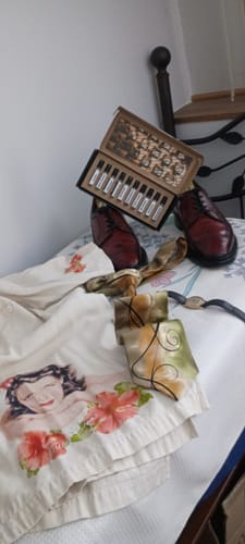 Recensore mostra il 'Set campioni fresche e pungenti' aperto, appoggiato su un letto con scarpe eleganti e una camicia.