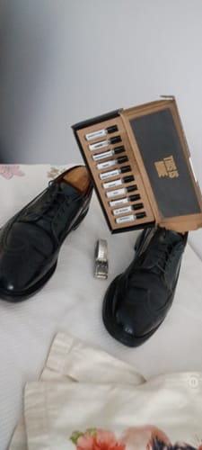 Un cliente mostra il set di campioni orientali e legnosi aperto, posizionato tra un paio di scarpe nere.