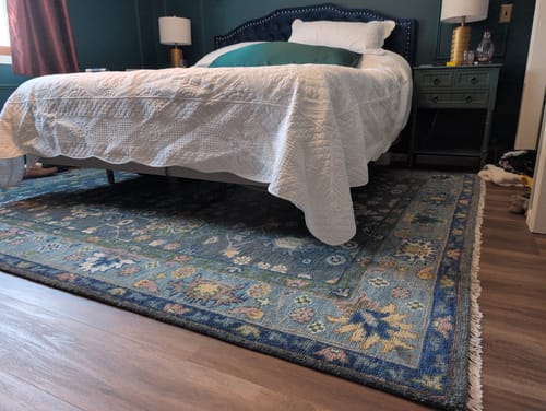 Customer's beautiful Turkish wool rug with a traditional design, shown in their bedroom under a bed.