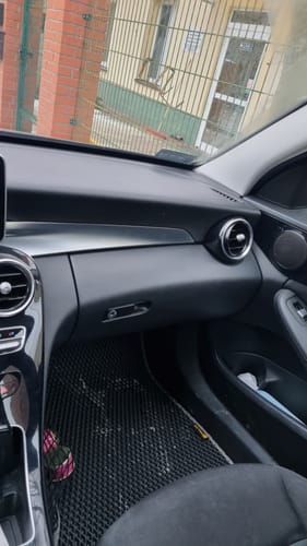 Recenzent pokazuje czarny, teksturowany dywanik samochodowy zainstalowany po stronie pasażera w samochodzie.