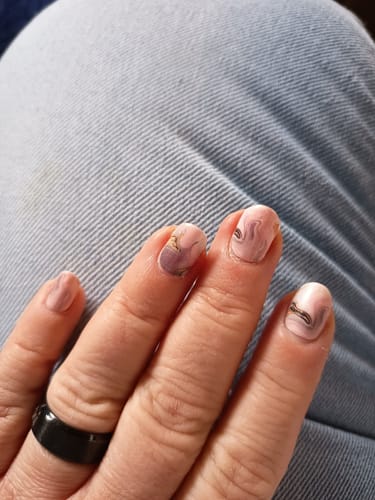 Nahaufnahme der Hand einer Kundin, die die 'Ballet Marble' Nagelfolien auf kurzen Nägeln trägt.
