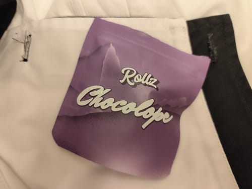Customer's purple packaging for Rollz Chocolope THC Chocolate seen in a pocket.