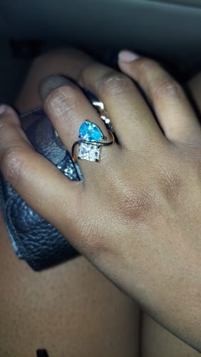 Close-up of a reviewer's hand wearing the Navae Birthstone Ring with a bright blue pear-cut stone and a clear radiant-cut stone.