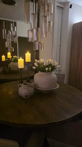 Recensent toont het witte tulpenboeket in een rustieke vaas op een eettafel.